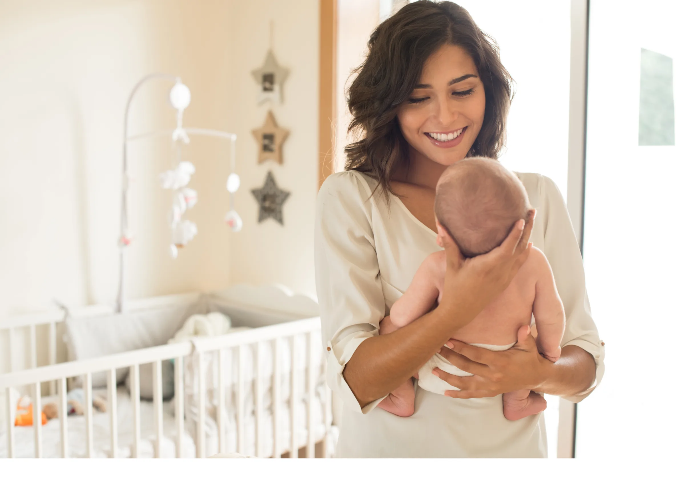 Mother holding her newborn baby in a softly lit nursery