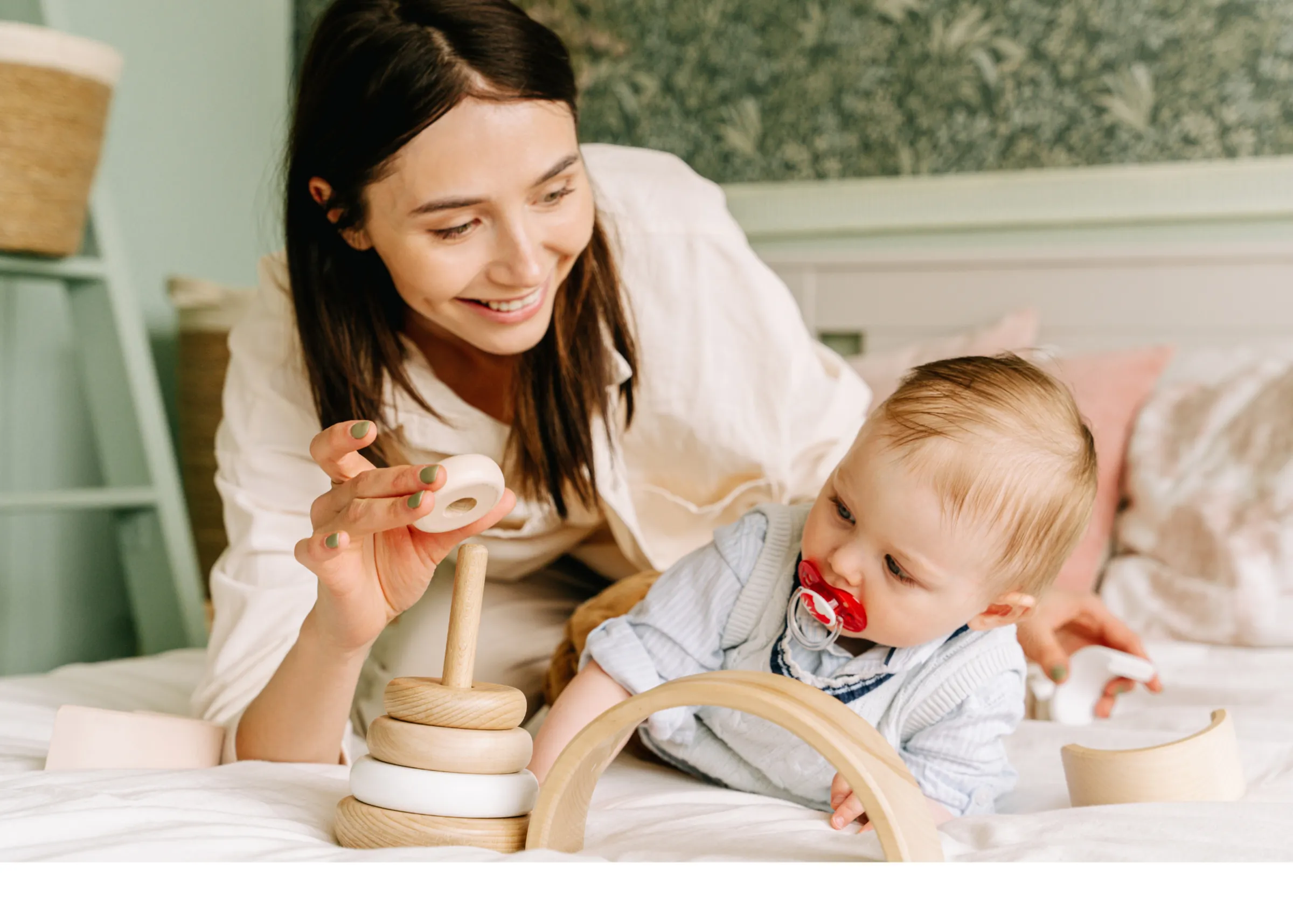 Mother playing with her baby on a sunlit bed